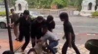 A man being restrained and kicked by several men outside a bar.