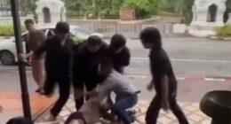 A man being restrained and kicked by several men outside a bar.