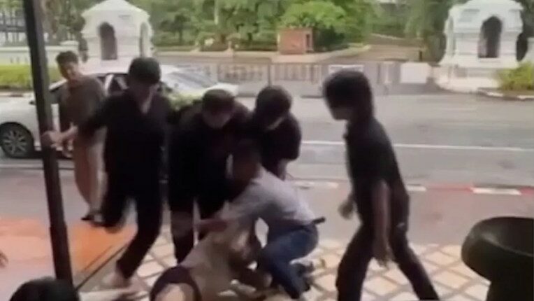 A man being restrained and kicked by several men outside a bar.