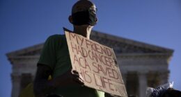 Protester holds sign that says 'My friend had cancer. ACA saved his life.'
