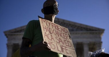 Protester holds sign that says 'My friend had cancer. ACA saved his life.'