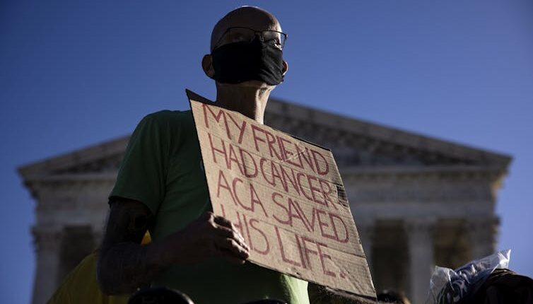 Protester holds sign that says 'My friend had cancer. ACA saved his life.'