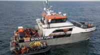 A Border Force vessel rescuing migrants from a small inflatable boat.