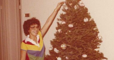Young woman decorating a Christmas tree.