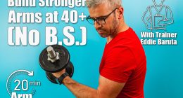 A man with gray hair and glasses exercises by lifting a dumbbell, showcasing strength and determination in a vibrant blue gym environment. Building Stronger Arms After 40 Could Be Way Easier Than You