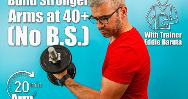 A man with gray hair and glasses exercises by lifting a dumbbell, showcasing strength and determination in a vibrant blue gym environment. Building Stronger Arms After 40 Could Be Way Easier Than You