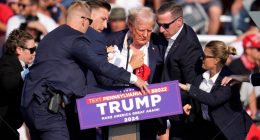 Donald Trump being helped off stage at a campaign event.