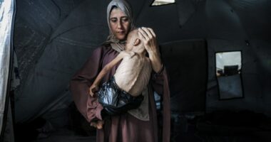 Malnourished child held by his mother in a tent.