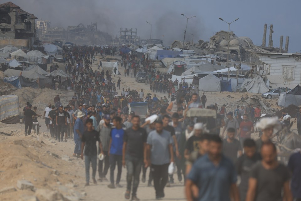 Palestinians carrying aid through a damaged area.