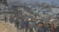 Palestinians carrying aid through a damaged area.