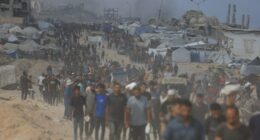 Palestinians carrying aid through a damaged area.