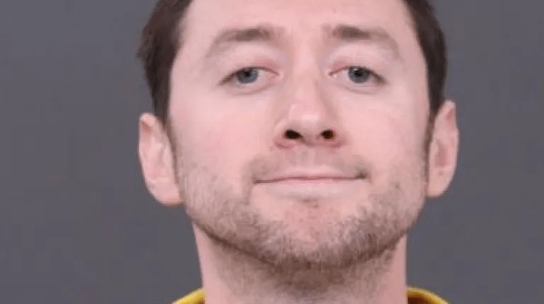 Mugshot of a man in a yellow shirt.