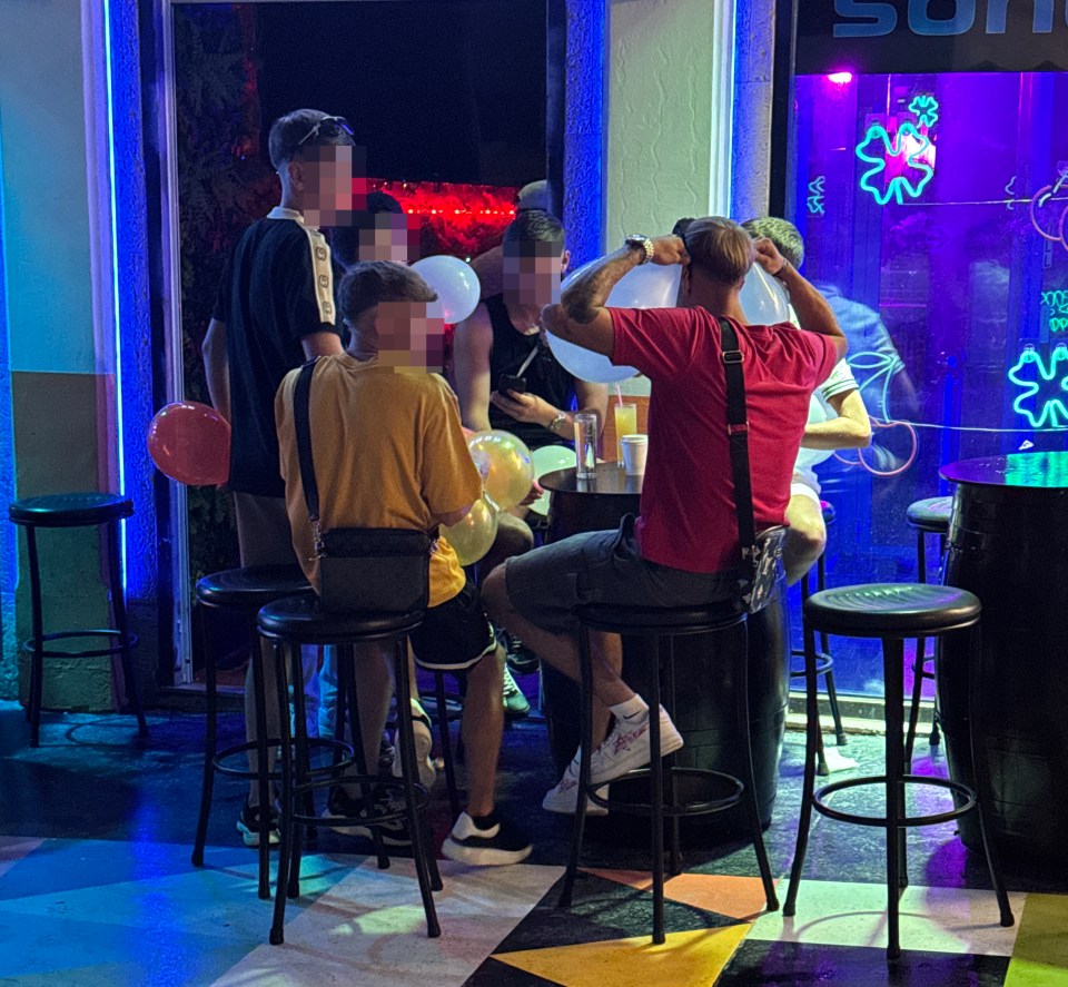 People inhaling nitrous oxide from balloons at a bar.