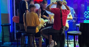 People inhaling nitrous oxide from balloons at a bar.