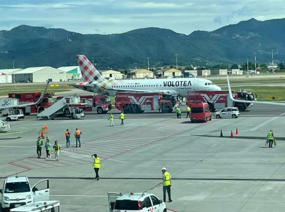 A Volotea airplane on a tarmac surrounded by emergency vehicles.