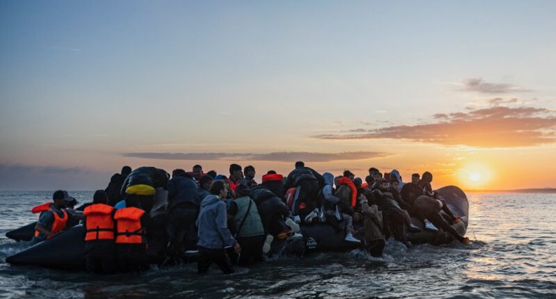 Migrants boarding a small inflatable boat at sunset.