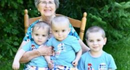 Grandmother with three grandsons sitting on a rocking chair.