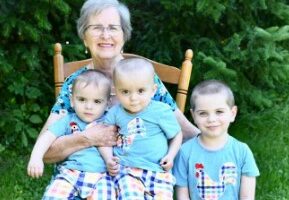 Grandmother with three grandsons sitting on a rocking chair.