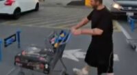 Man pushing a shopping cart in a parking lot.