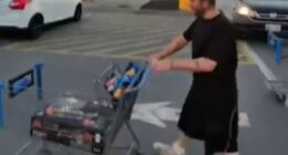 Man pushing a shopping cart in a parking lot.