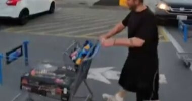 Man pushing a shopping cart in a parking lot.