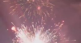 Fireworks exploding over water.