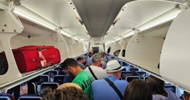 Passengers standing in an airplane aisle.