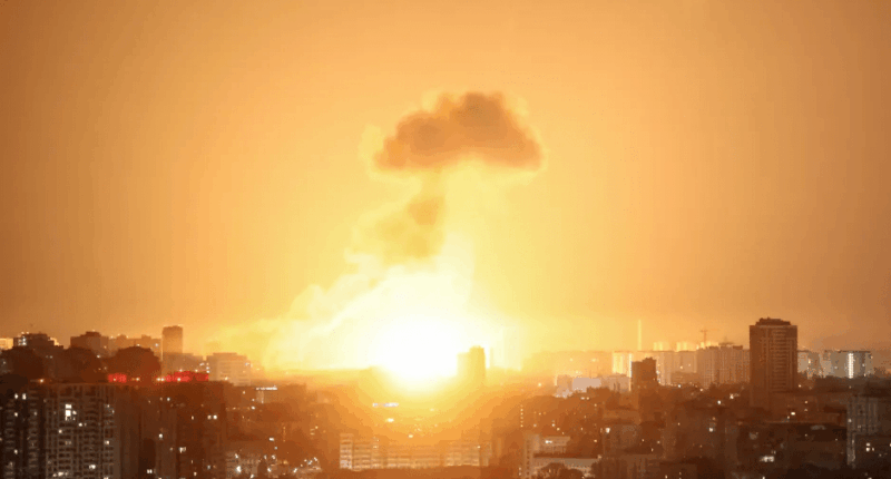 Large explosion over a city at night.