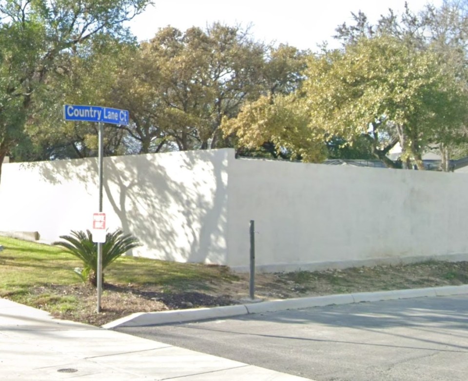 High, white fence on a residential street.