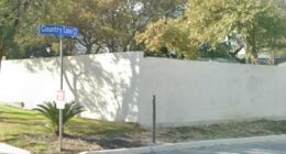 High, white fence on a residential street.