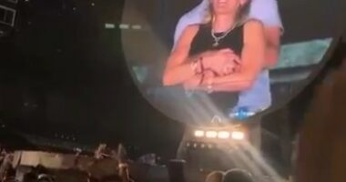 Large screen showing a couple embracing at a Coldplay concert.