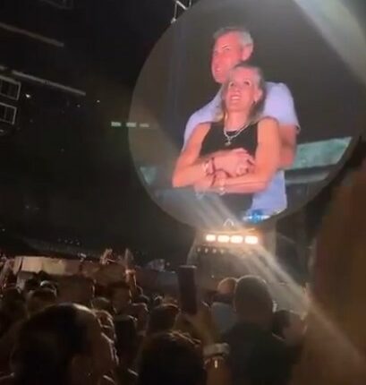 Large screen showing a couple embracing at a Coldplay concert.