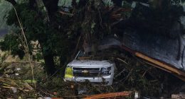 SUV buried in debris after a flood.