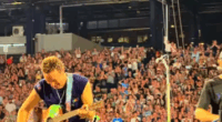 Chris Martin of Coldplay playing guitar on stage.