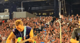 Chris Martin of Coldplay playing guitar on stage.
