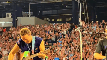 Chris Martin of Coldplay playing guitar on stage.