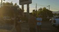 Police officer speaking with two men outside a Safeway.