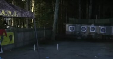 Nighttime photo of an archery range with targets and people.