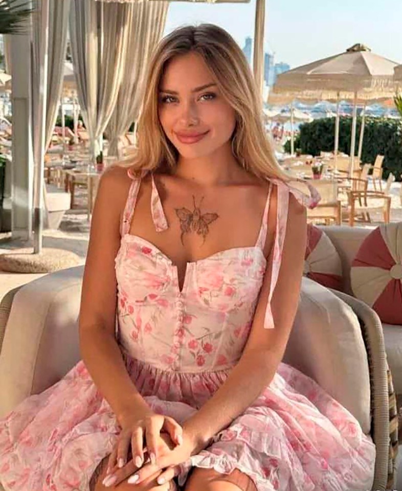 Woman in floral dress sitting outdoors.