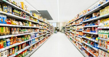 Aisle in a supermarket stocked with various food and drink items.