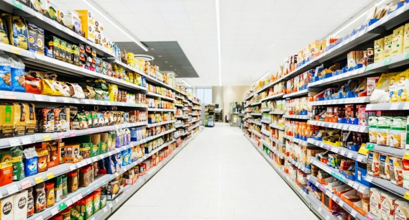 Aisle in a supermarket stocked with various food and drink items.