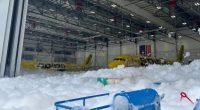 Two Spirit Airlines planes covered in foam inside a hangar.