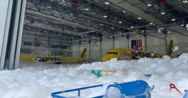 Two Spirit Airlines planes covered in foam inside a hangar.