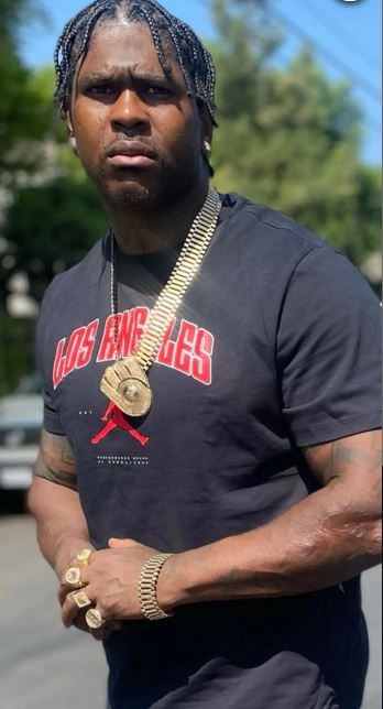 Man wearing a black Los Angeles shirt and gold jewelry.