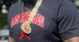 Man wearing a black Los Angeles shirt and gold jewelry.