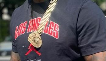 Man wearing a black Los Angeles shirt and gold jewelry.