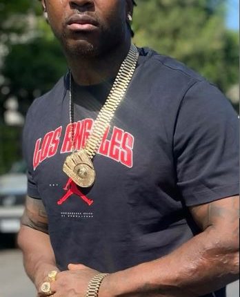 Man wearing a black Los Angeles shirt and gold jewelry.