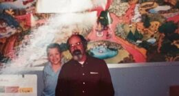 Photo of a man and a boy in front of a mural.