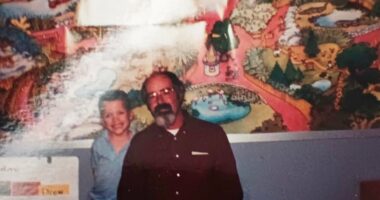 Photo of a man and a boy in front of a mural.