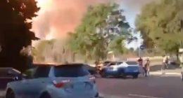 Large plume of smoke billowing near parked cars.